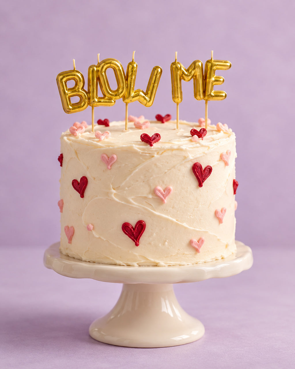 Gold "BLOW ME" letter candles on a heart decorated cake