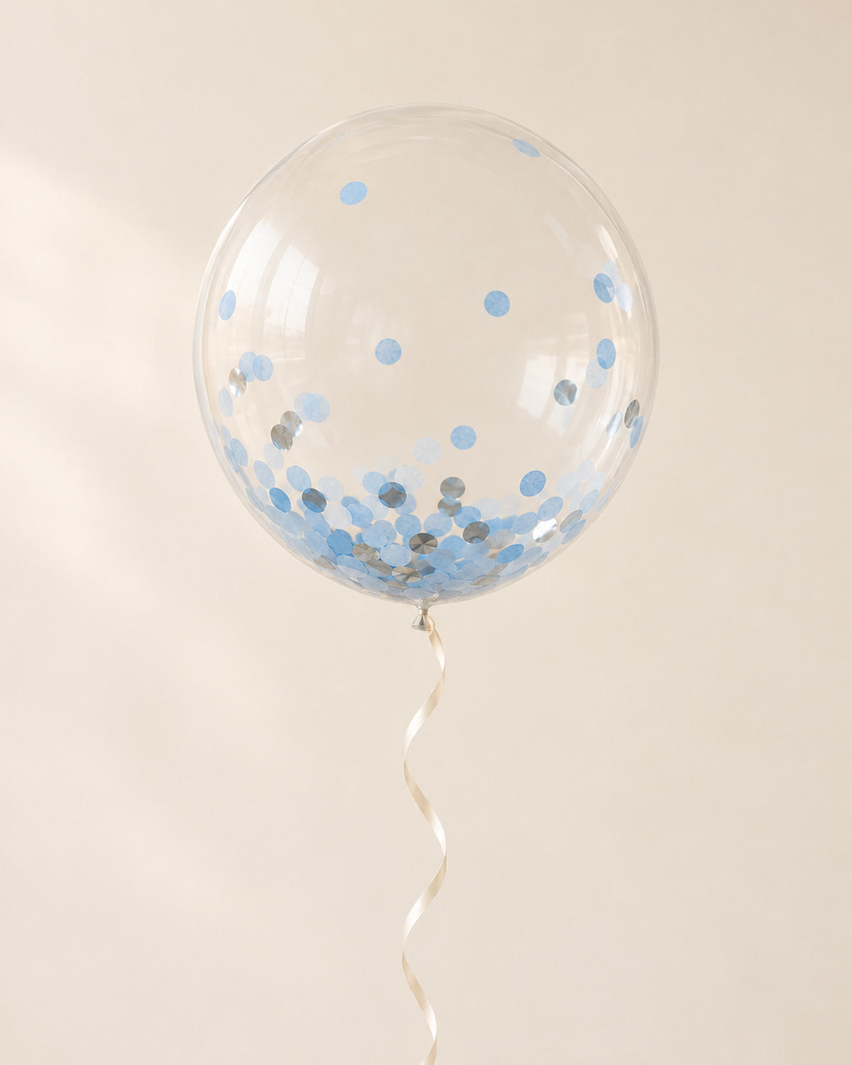 Clear bubble balloon filled with blue round confetti and finished with an ribbon