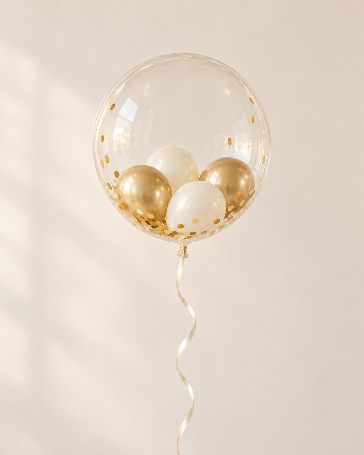 Clear bubble balloon filled with gold and ivory mini balloons and gold confetti, finished with an ribbon