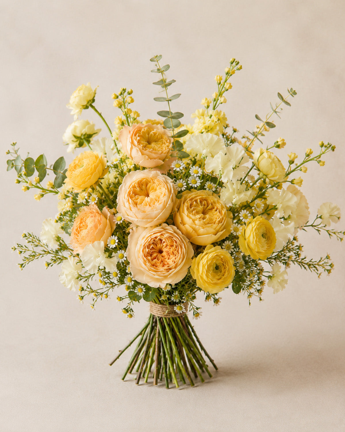Champagne Morning bouquet with peach roses, yellow ranunculus, white flowers, and greenery
