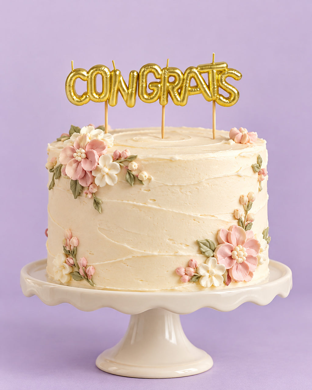 Gold "CONGRATS" letter candles on a frosted cake