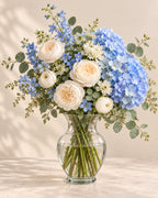 Blue Cloud bouquet with blue hydrangea, white peonies, blue delphinium, and eucalyptus arranged in a vase
