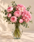 Pink Cloud bouquet with pink peonies, hydrangea, and eucalyptus arranged in a clear glass vase
