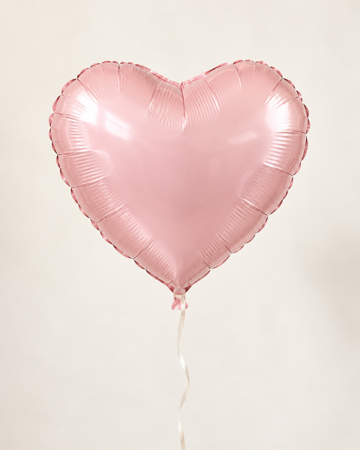 Blush pink heart-shaped foil balloon with a thin ribbon