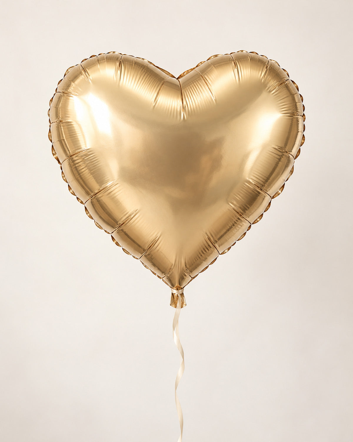 Champagne gold heart-shaped foil balloon with a thin ribbon