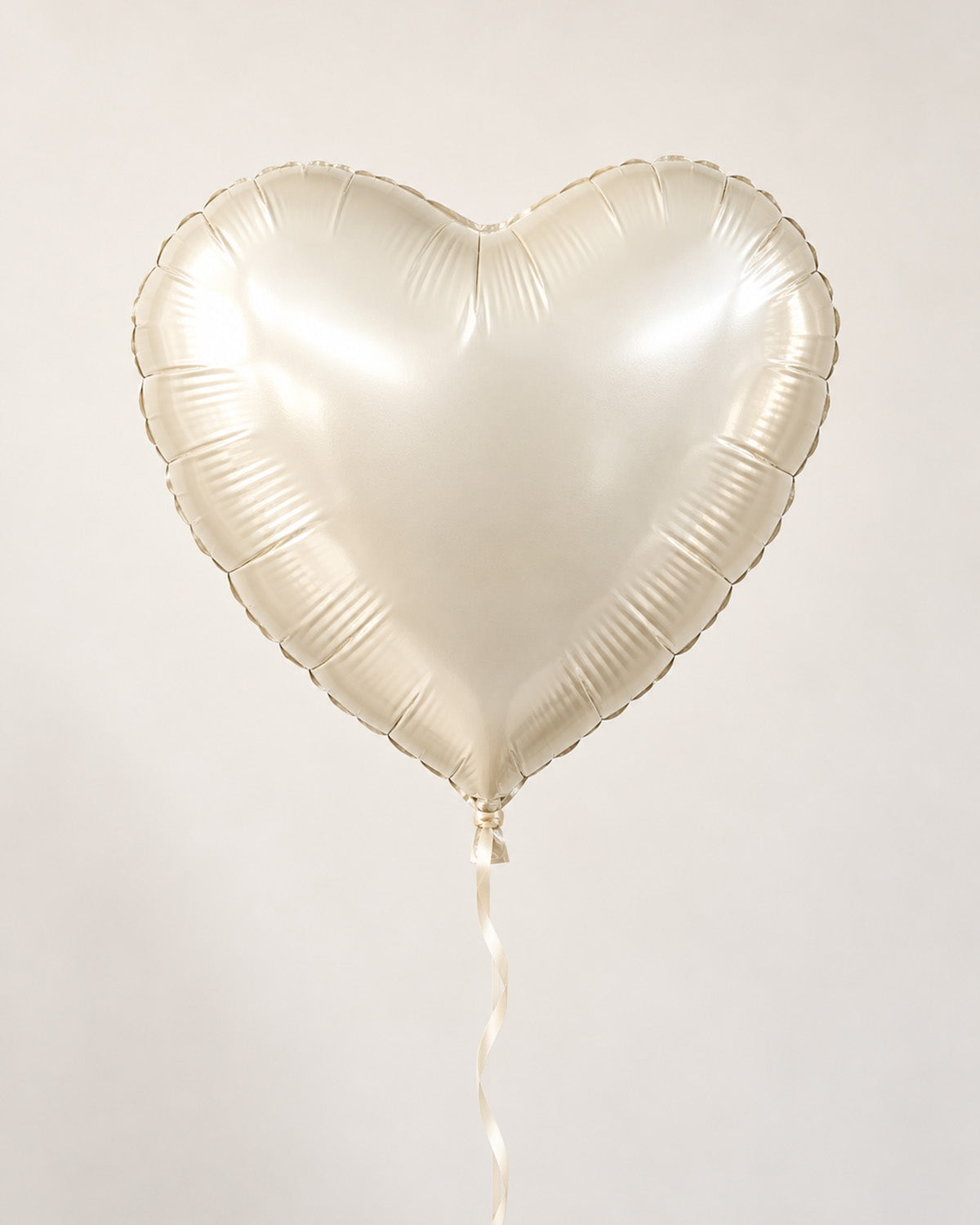 Ivory heart-shaped foil balloon with a thin ribbon