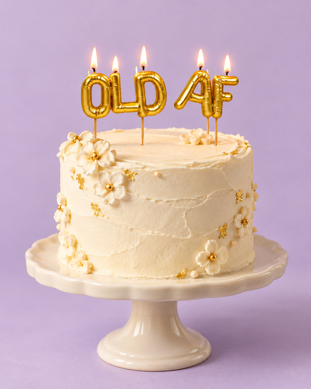 Lit gold "OLD AF" letter candles on a frosted cake