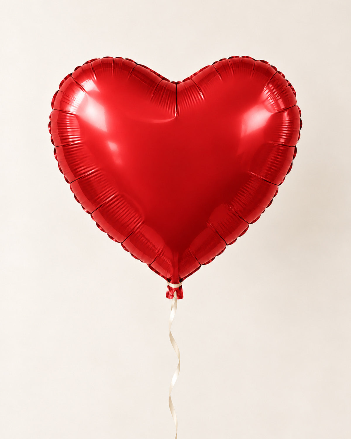 Red heart-shaped foil balloon with a thin ribbon