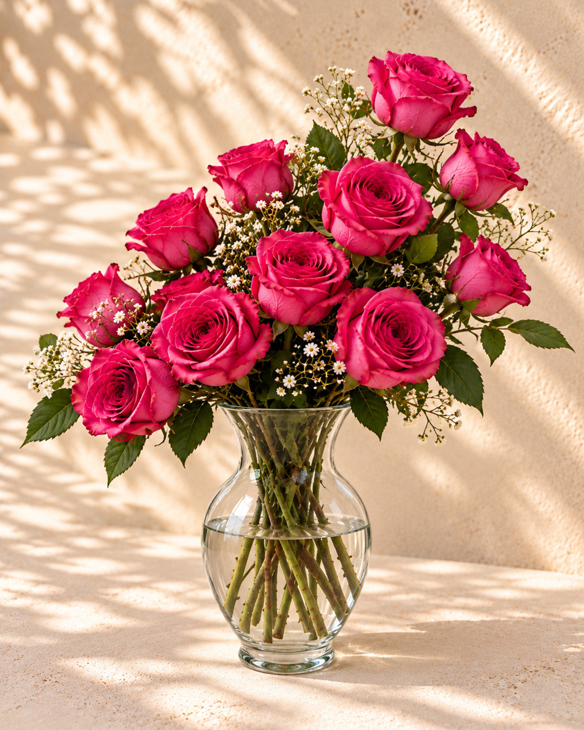 Fuchsia roses with baby's breath in a clear glass vase