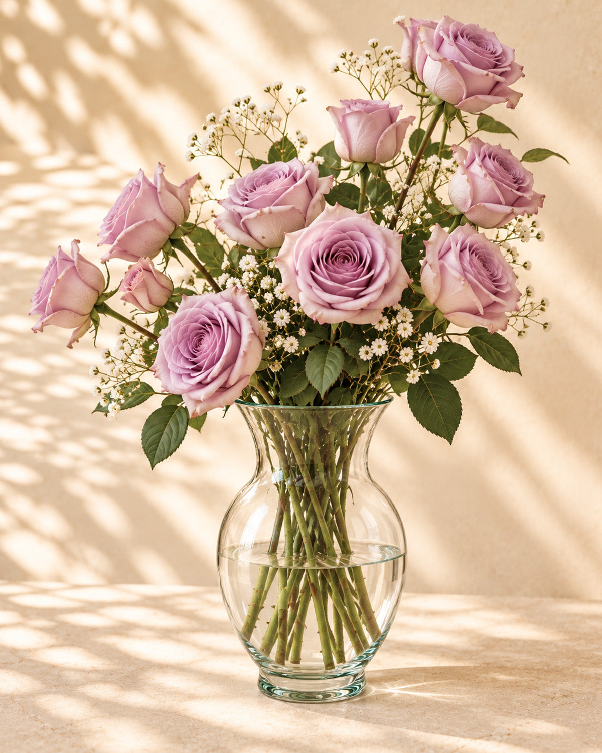 Lavendar roses with baby's breath in a clear glass vase