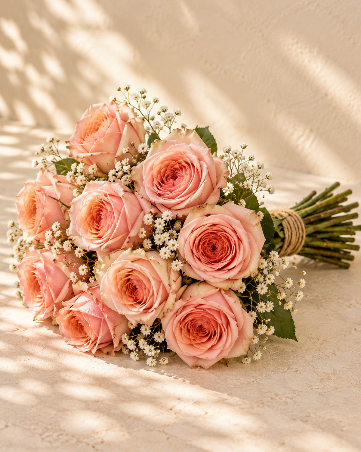 Peach roses with baby's breath, greenery, and twine